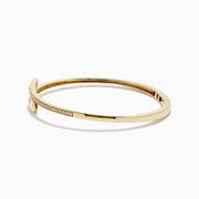 The D'Oro 14k Yellow Gold Diamond Bypass Bangle showcases two overlapping ends tipped with pear-shaped diamonds and a band lined with small round diamonds.