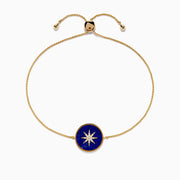 The 14K Yellow Gold Lapis and Diamond Compass Bolo Bracelet features an adjustable chain with a round lapis-inspired blue enamel center charm, adorned with a white starburst design and sparkling diamond accents.