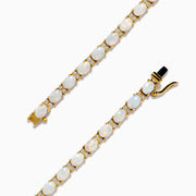 The 14K Yellow Gold Opal and Diamond Tennis Bracelet features a row of round white opals set in gold prongs, accented with diamonds, displayed on a white background.