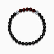The Men's Meteorite and Tiger's Eye Beaded Bracelet features mainly black beads, five dark red tiger's eye beads at the center, flanked by two silver meteorite beads, strung on elastic and displayed against a white background.