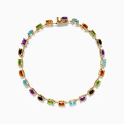 The 14K Yellow Gold Cushion Cut Multi Color Gemstone Tennis Bracelet showcases a row of cushion-cut multicolored gemstones set in yellow gold, displayed against a white background.