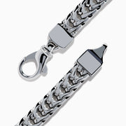 The Mens 925 Sterling Silver Onyx and Black Diamond Bracelet features a woven chain design, a rectangular onyx center stone in a decorative frame, black diamond accents, and a secure lobster clasp closure.