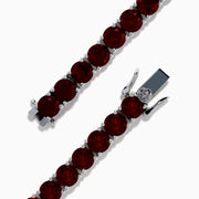 The 925 Sterling Silver Garnet Bracelet features round, deep red garnets set in individual prongs along a sleek tennis chain, beautifully arranged in a circular shape on a white background.
