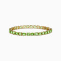 The 14K Yellow Gold Peridot Tennis Bracelet 13.50 TCW features evenly spaced round and square green gems, shown against a white background.