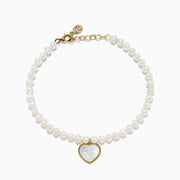 The 14K Gold Fresh Water Pearl and Mother of Pearl Heart Charm Bracelet features a gold clasp and extender, with a heart charm outlined in gold and filled with iridescent mother of pearl, shown against a white background.