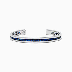 The Men's 925 Sterling Silver and Blue Sapphire Bracelet features a row of blue sapphires at the center and black chevron accents on the edges, offering a bold update to the classic blue sapphire bracelet.