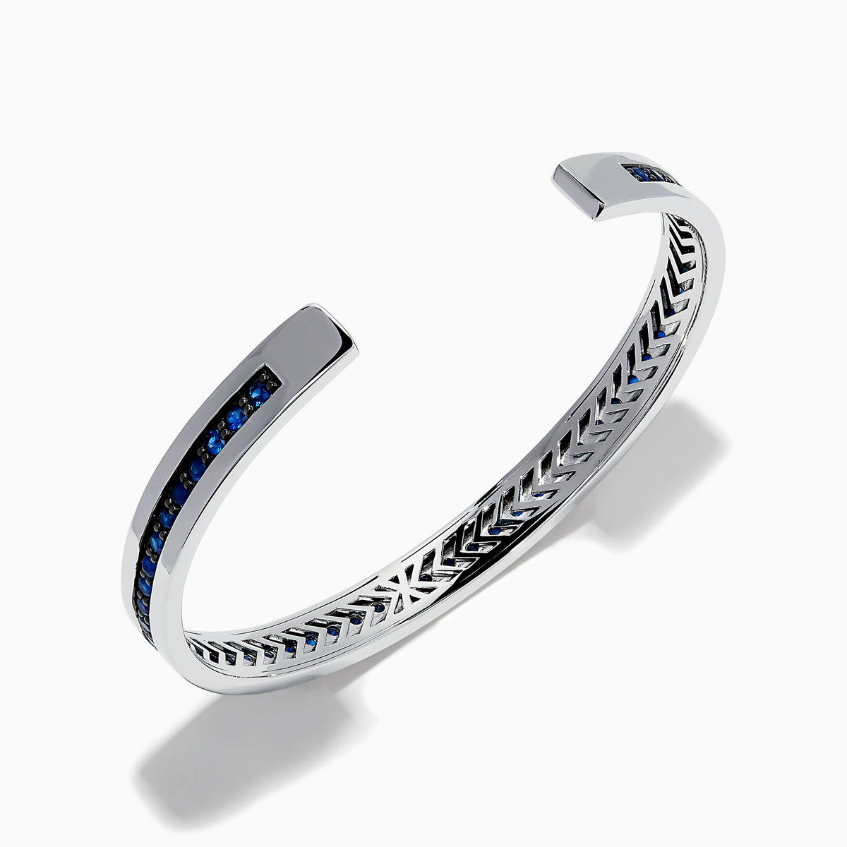 The Men's 925 Sterling Silver and Blue Sapphire Bracelet features a row of blue sapphires at the center and black chevron accents on the edges, offering a bold update to the classic blue sapphire bracelet.
