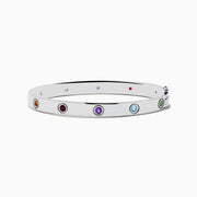 The 925 Sterling Silver Multi Gemstone and Diamond Bangle features small, round gemstones in vibrant red, purple, green, blue, and orange hues set evenly along a sleek silver band.