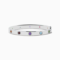 The 925 Sterling Silver Multi Gemstone and Diamond Bangle features small, round gemstones in vibrant red, purple, green, blue, and orange hues set evenly along a sleek silver band.