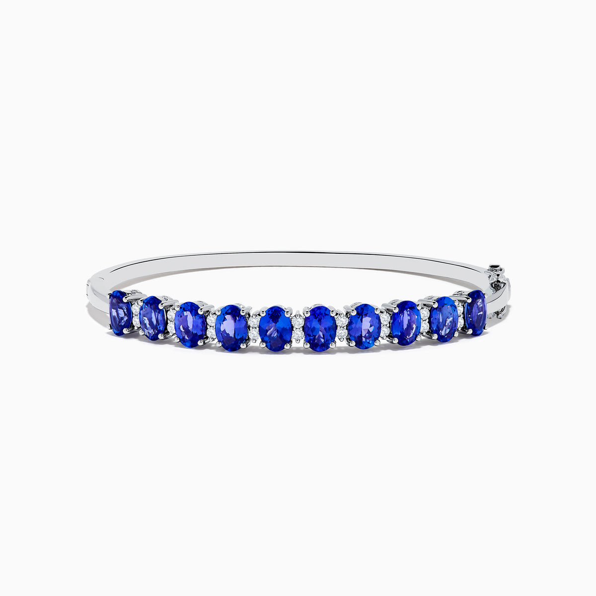 The 14K White Gold Tanzanite and Diamond Bangle features a row of oval-shaped blue tanzanites set in the center, displayed against a white background.