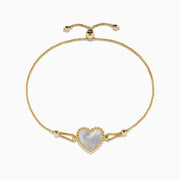 The 14K Yellow Gold Mother of Pearl Heart Bolo Bracelet features a central heart-shaped Mother of Pearl framed by gold beads, with an adjustable slider clasp on a delicate gold chain.
