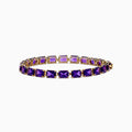 The 14K Yellow Gold Radiant Cut Amethyst Tennis Bracelet showcases a row of radiant cut amethysts in prong settings, displayed against a white background.