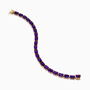 The 14K Yellow Gold Radiant Cut Amethyst Tennis Bracelet showcases a row of radiant cut amethysts in prong settings, displayed against a white background.