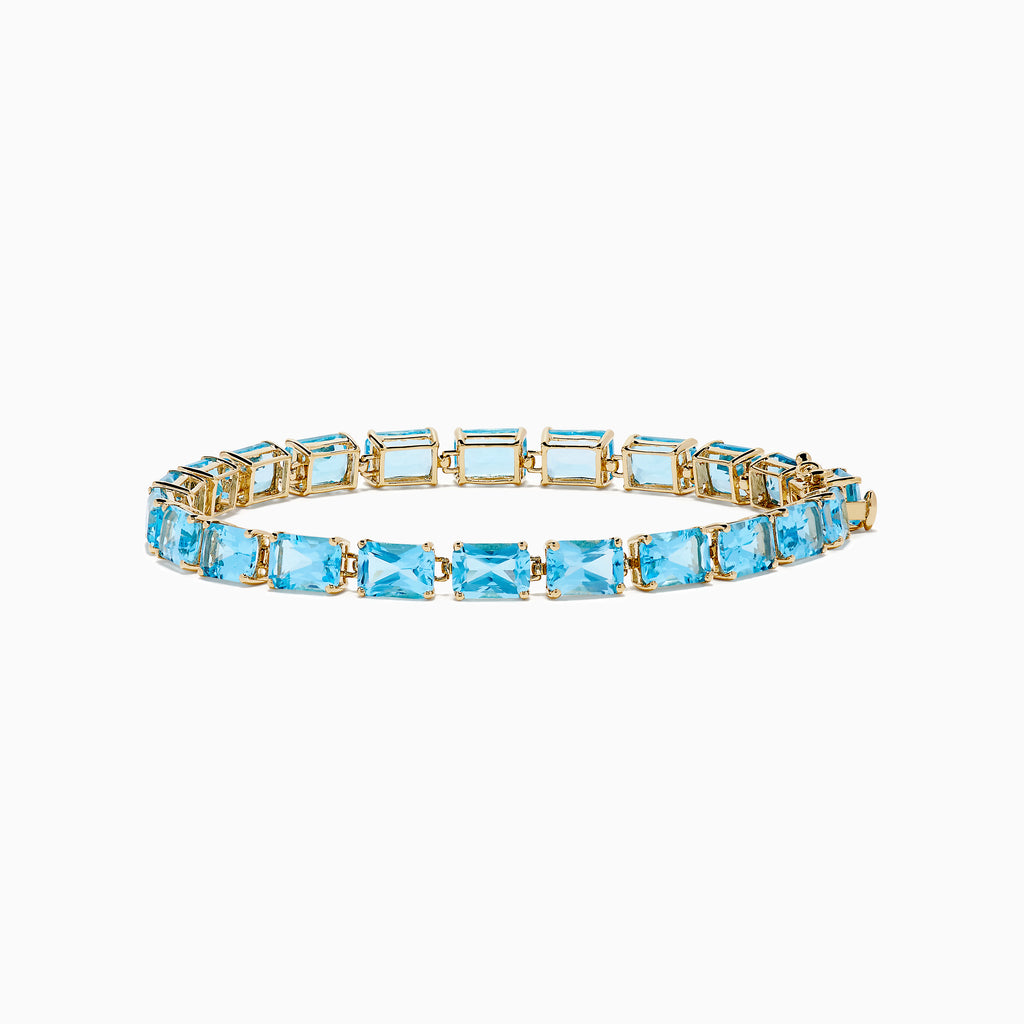 The Ocean Bleu 14K Yellow Gold Radiant Cut Blue Topaz Tennis Bracelet features rectangular blue topaz gemstones set in individual links, displayed on a plain white background.