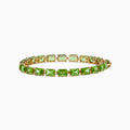 The 14K Yellow Gold Radiant Cut Peridot Tennis Bracelet features rectangular green peridot gemstones evenly spaced and connected, displayed on a white background.