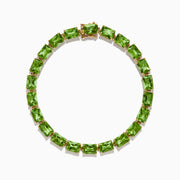 The 14K Yellow Gold Radiant Cut Peridot Tennis Bracelet features rectangular green peridot gemstones evenly spaced and connected, displayed on a white background.