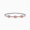 This Platinum and 14K Rose Gold Pink and White Diamond Bangle features three teardrop-shaped pink gemstone clusters framed by diamonds, creating an elegant look with evenly spaced gems along its slender silver-toned band.