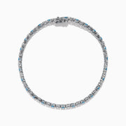 The Lab Grown Blue and White Diamond Tennis Bracelet in 14K White Gold features alternating round blue and white diamonds set in a continuous line, shown against a white background.