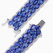 The Nahla Siri Sterling Silver Tanzanite and Diamond Bracelet features three rows of oval-cut tanzanite gemstones in prong settings on an intricate, reflective sterling silver band, displayed against a white background.