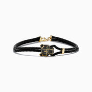 A black braided leather bracelet featuring a signature 14K yellow gold panther center with black diamond and tsavorite accents, finished with a gold clasp for men.