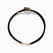A black braided leather bracelet featuring a signature 14K yellow gold panther center with black diamond and tsavorite accents, finished with a gold clasp for men.