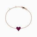 The 14K Rose Gold Pave Ruby Heart Bracelet features a delicate chain with a central heart-shaped charm set with rubies and secured by a lobster clasp.