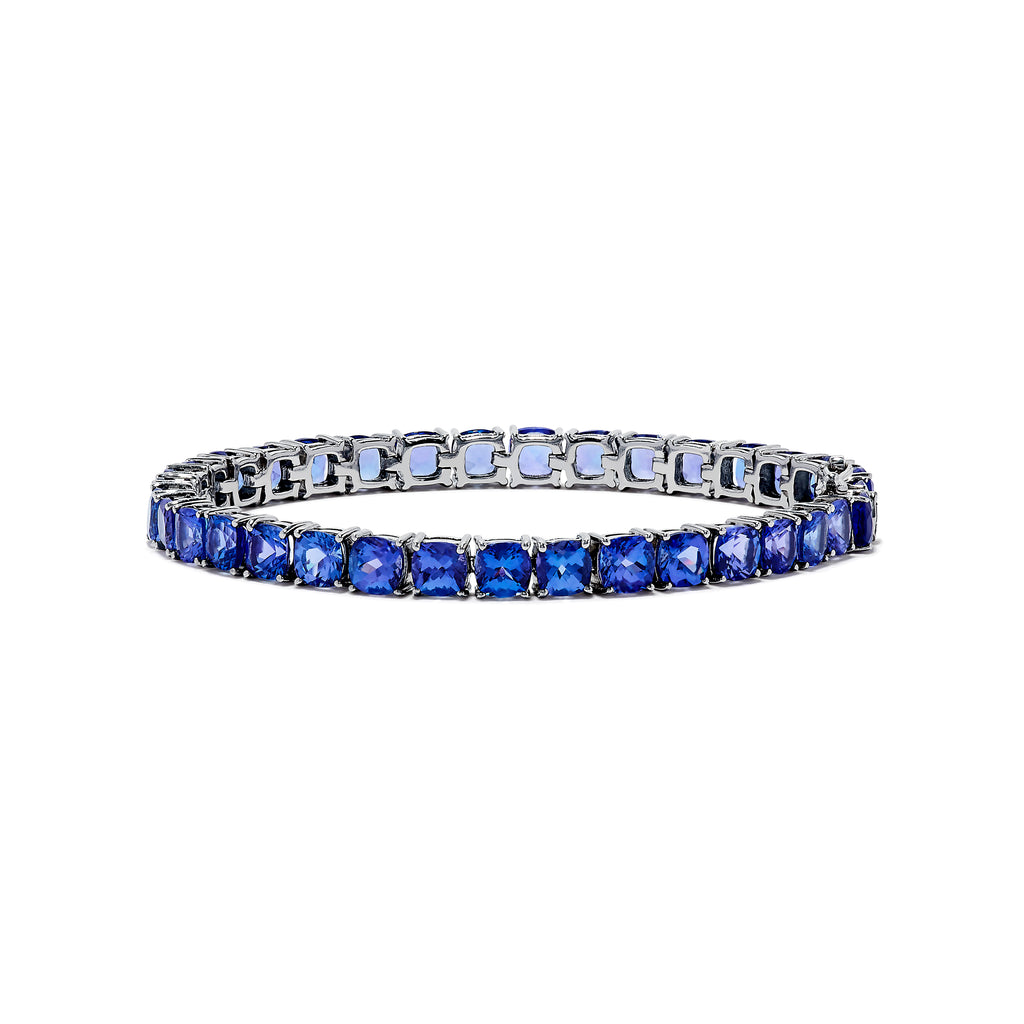 The Nahla Siri Sterling Silver Tanzanite Tennis Bracelet showcases a row of square-cut tanzanite gemstones set evenly around the band, displayed against a white background.