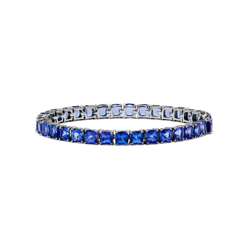 The Nahla Siri Sterling Silver Tanzanite Tennis Bracelet showcases a row of square-cut tanzanite gemstones set evenly around the band, displayed against a white background.