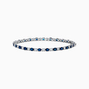 The Royale Bleu 14k White Gold Blue Sapphire and Diamond Bracelet showcases alternating round blue sapphires and clear diamonds in a continuous line, beautifully set against a plain white background.
