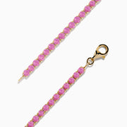 The 14K Yellow Gold Pink Sapphire Tennis Bracelet features small round pink sapphires in a continuous yellow gold setting with a gold clasp, displayed on a white background.