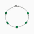 The 14K White Gold Emerald and Diamond Tennis Bracelet features a silver chain with small round white stones and five evenly spaced rectangular emeralds, displayed on a white background.