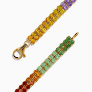 The Watercolors 14K Yellow Gold Multi Sapphire Double Lined Tennis Bracelet showcases two rows of sapphires in a vibrant rainbow gradient, with colors flowing from red and orange to yellow, green, blue, and purple.