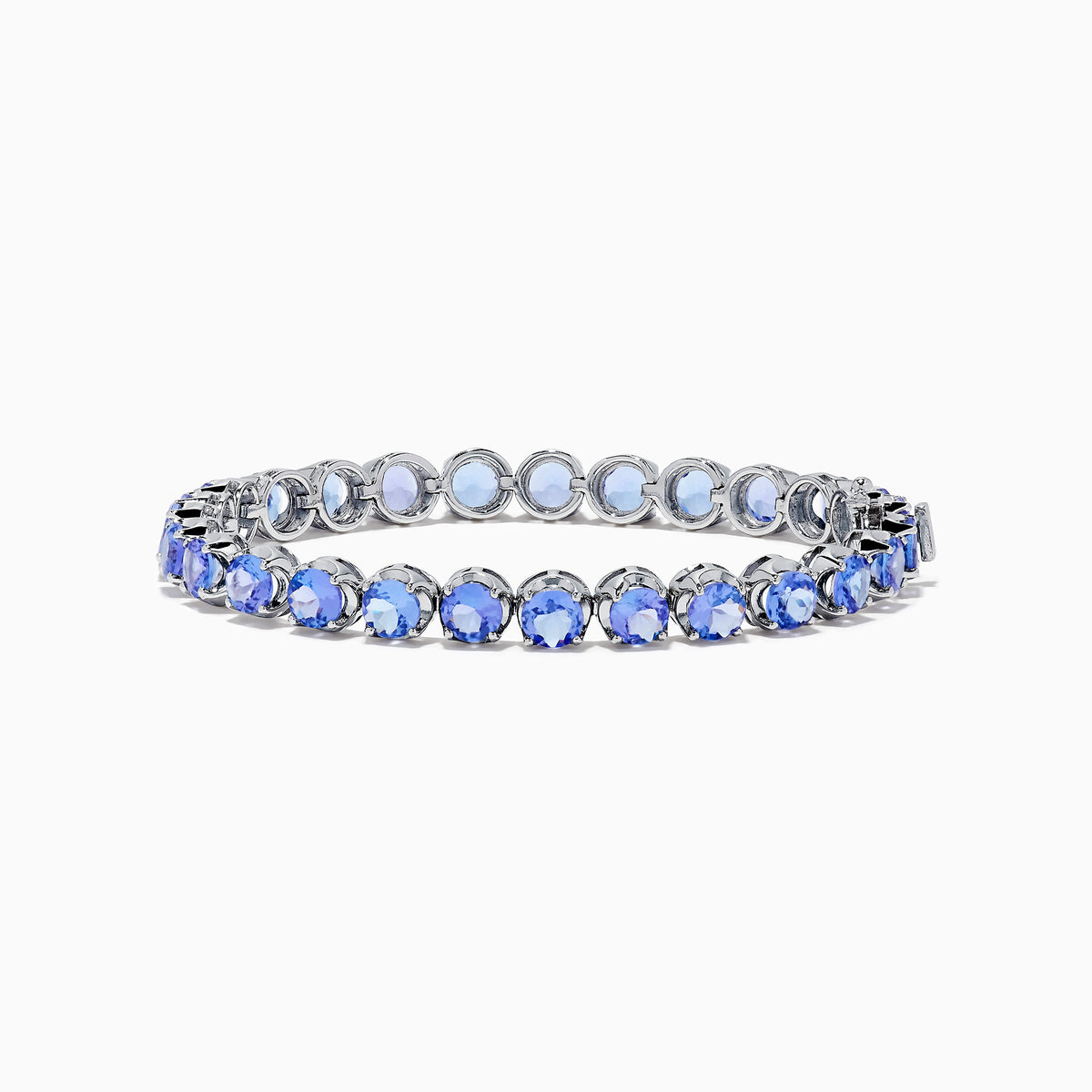 The Nahla Siri Sterling Silver Tanzanite Tennis Bracelet showcases a row of round, faceted tanzanite gemstones in prong settings, elegantly displayed against a white background.
