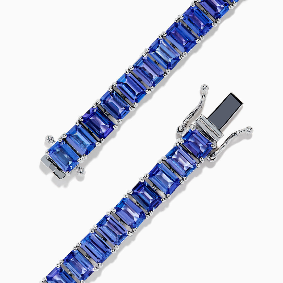 The Nahla Siri Sterling Silver Emerald Cut Tanzanite Tennis Bracelet, featuring a row of individually prong-set gemstones, is elegantly displayed on a plain white background.