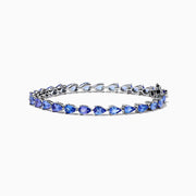 The Nahla 925 Sterling Silver Pear Tanzanite Tennis Bracelet showcases a continuous row of pear-shaped tanzanite gemstones, each set in individual prongs, and secured with a sturdy clasp.