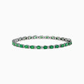 The 925 Sterling Silver Emerald and Diamond Tennis Bracelet features a continuous row of oval green gemstones and diamonds, each prong-set for elegance, reminiscent of an emerald bracelet, displayed on a white background.