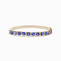 The Nahla 14K Yellow Gold Tanzanite and Diamond Bangle features alternating triangular tanzanite stones and sparkling diamonds in a repeating pattern along the gold band.