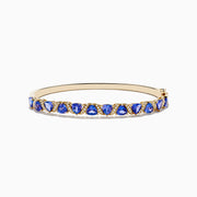 The Nahla 14K Yellow Gold Tanzanite and Diamond Bangle features alternating triangular tanzanite stones and sparkling diamonds in a repeating pattern along the gold band.