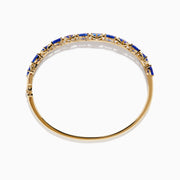 The Nahla 14K Yellow Gold Tanzanite and Diamond Bangle features alternating triangular tanzanite stones and sparkling diamonds in a repeating pattern along the gold band.
