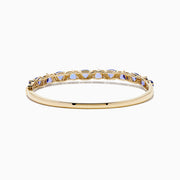The Nahla 14K Yellow Gold Tanzanite and Diamond Bangle features alternating triangular tanzanite stones and sparkling diamonds in a repeating pattern along the gold band.