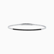 The Caviar 14K White Gold Black Diamond Bangle is a slim silver bracelet adorned with a row of small black diamonds, reminiscent of caviar, displayed on a white background.