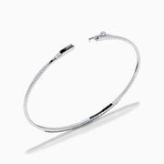 The Caviar 14K White Gold Black Diamond Bangle is a slim silver bracelet adorned with a row of small black diamonds, reminiscent of caviar, displayed on a white background.