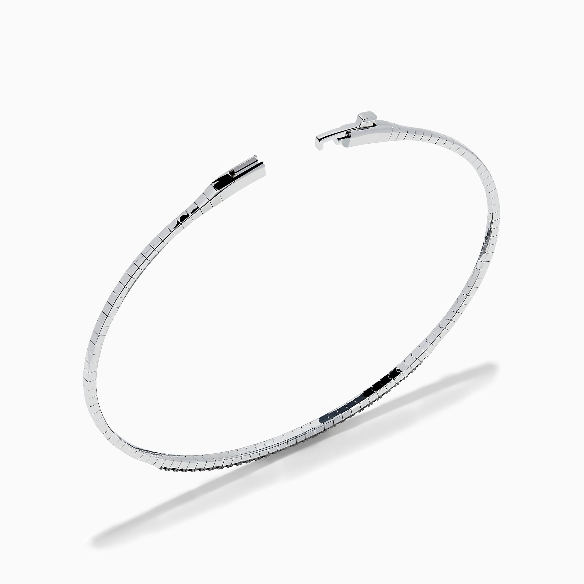 The Caviar 14K White Gold Black Diamond Bangle is a slim silver bracelet adorned with a row of small black diamonds, reminiscent of caviar, displayed on a white background.