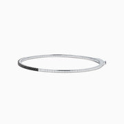 The Caviar 14K White Gold Black Diamond Bangle is a slim silver bracelet adorned with a row of small black diamonds, reminiscent of caviar, displayed on a white background.