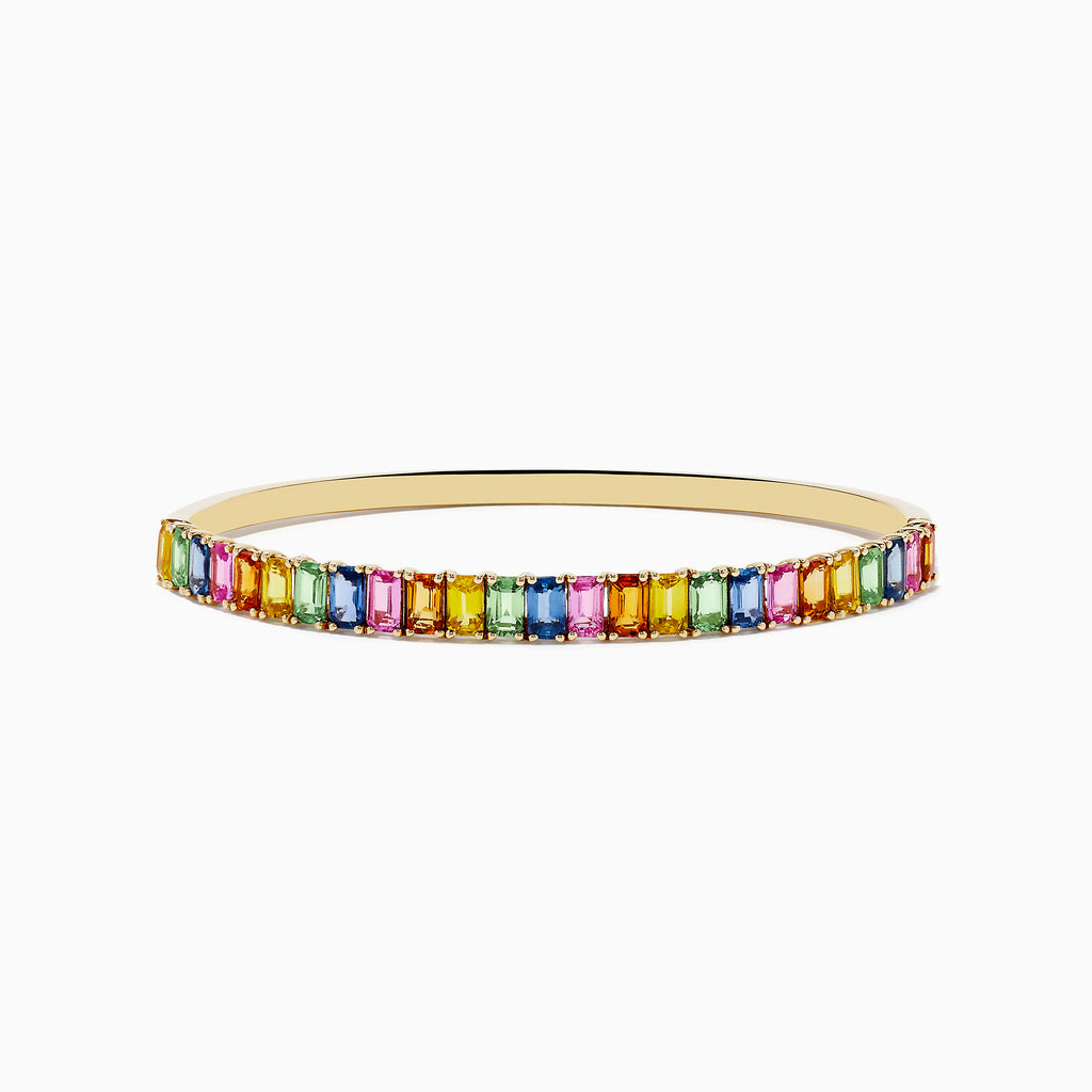 The Watercolor 14k Yellow Gold Emerald Cut Multi Sapphire Bangle features multicolored gemstones in a continuous row, creating a vibrant look.