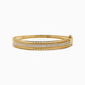The D'Oro 14K Yellow Gold Diamond Bangle showcases rows of sparkling center diamonds, a textured border, and a secure hinged clasp for timeless elegance.