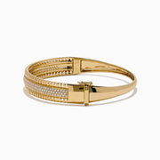 The D'Oro 14K Yellow Gold Diamond Bangle showcases rows of sparkling center diamonds, a textured border, and a secure hinged clasp for timeless elegance.