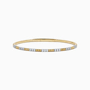 The 14K Two Tone Gold Diamond Flexible Bangle features alternating sections of small round white diamonds and plain gold, offering timeless elegance and a hint of sparkle. Shown on a simple white background.