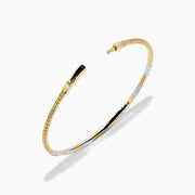 The 14K Two Tone Gold Diamond Flexible Bangle features alternating sections of small round white diamonds and plain gold, offering timeless elegance and a hint of sparkle. Shown on a simple white background.