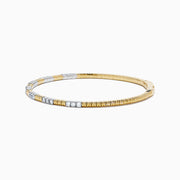 The 14K Two Tone Gold Diamond Flexible Bangle features alternating sections of small round white diamonds and plain gold, offering timeless elegance and a hint of sparkle. Shown on a simple white background.